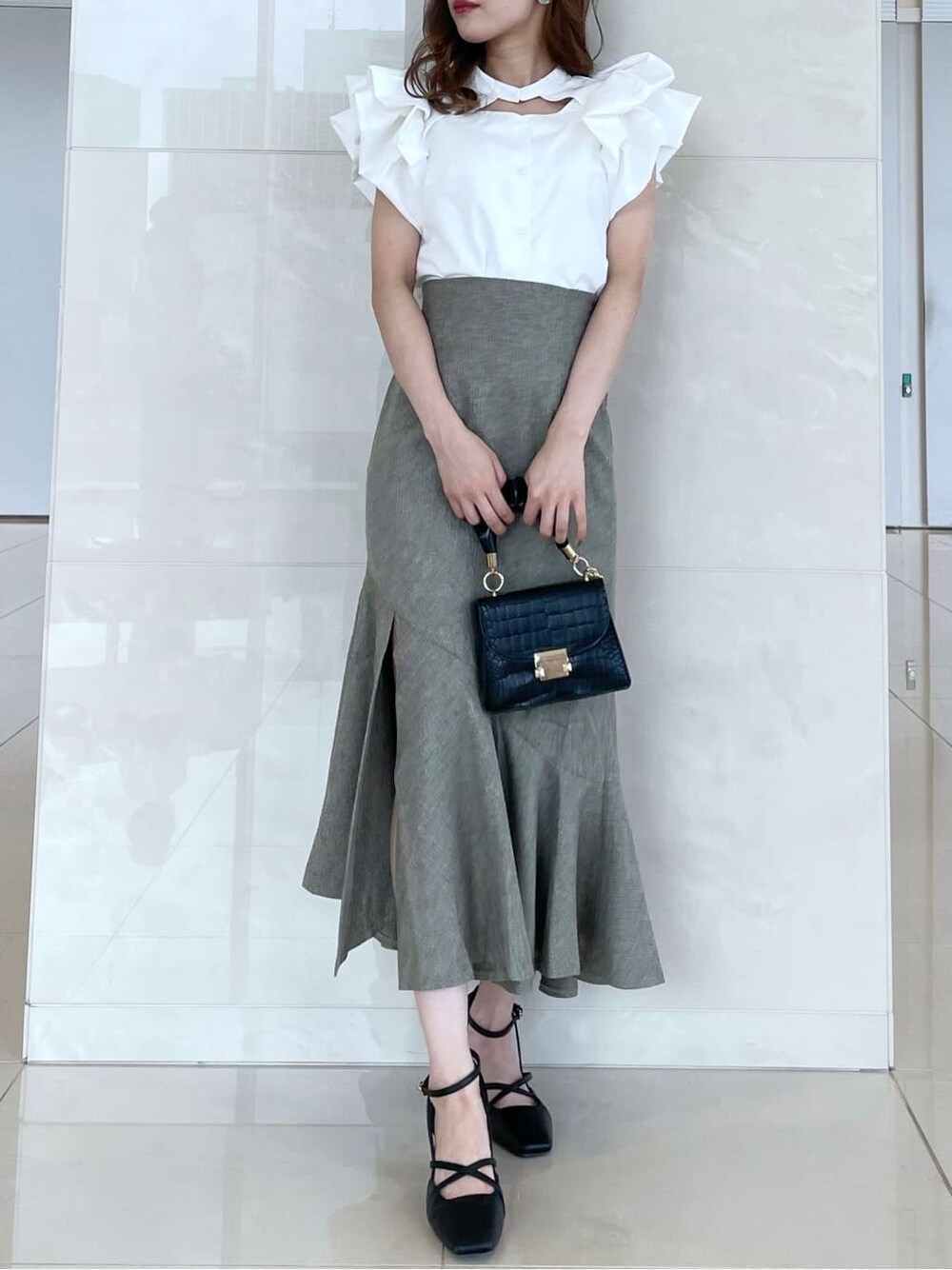 ホワイト系のシャツ/ブラウス、グリーン系のスカート、ブラック系のパンプスを着用したレディースの秋コーディネートの1枚目の写真