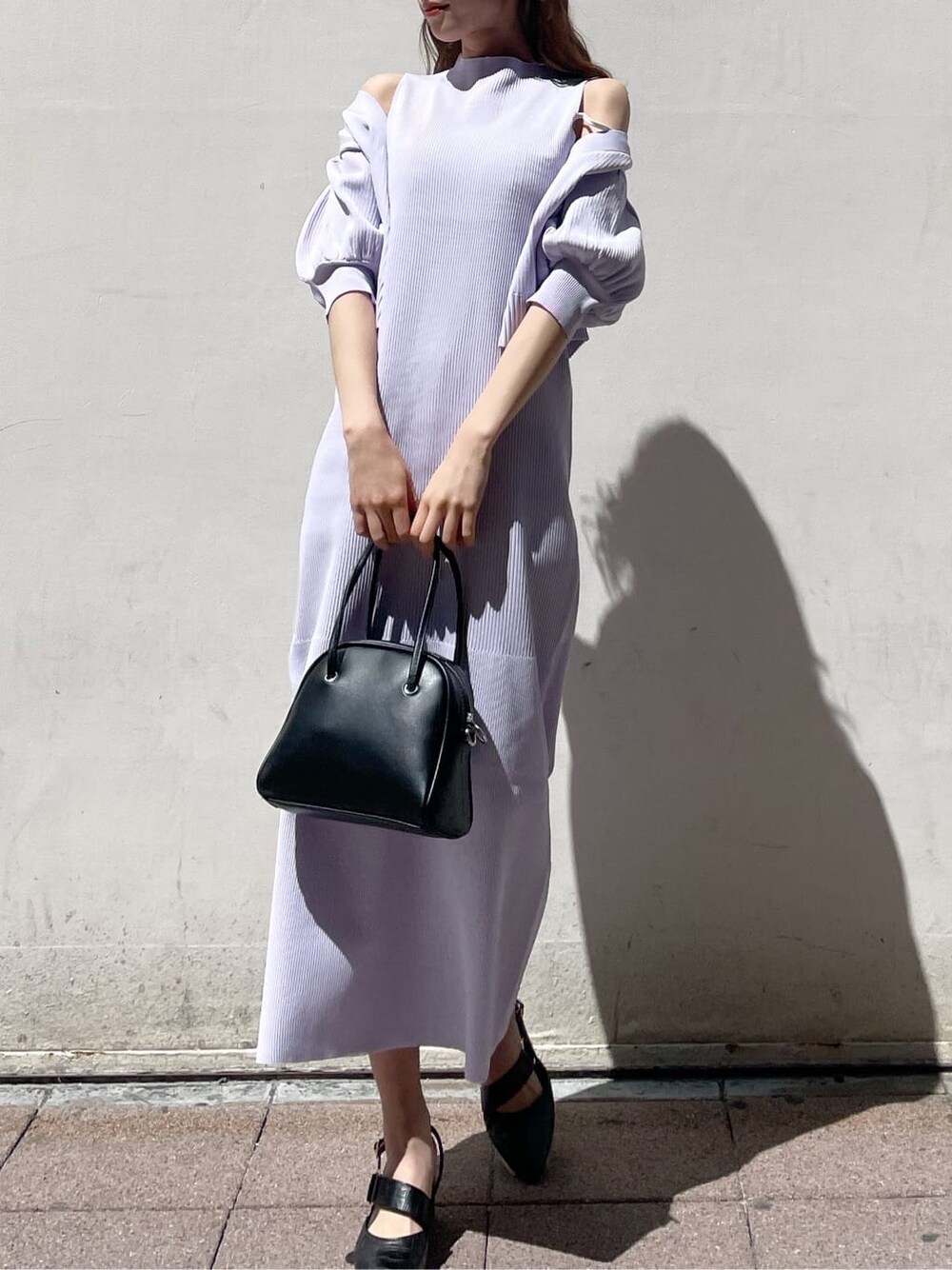 パープル系のワンピース、ブラック系のパンプス、ブラック系のハンドバッグを着用したレディースの春コーディネートの1枚目の写真