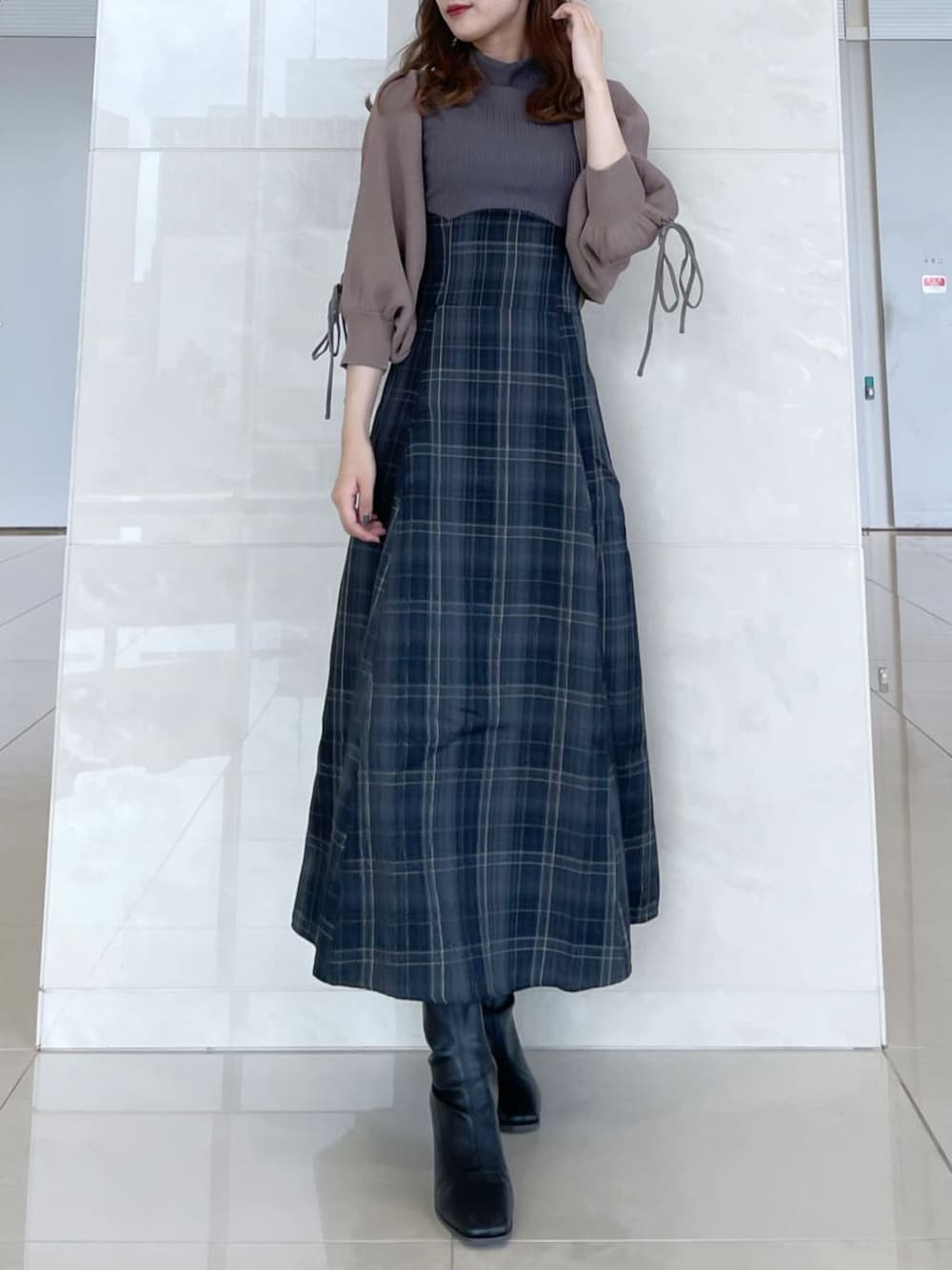 グレー系のワンピース、ブラック系のブーツ、ブラウン系のカーディガン/ボレロを着用したレディースの秋コーディネートの1枚目の写真