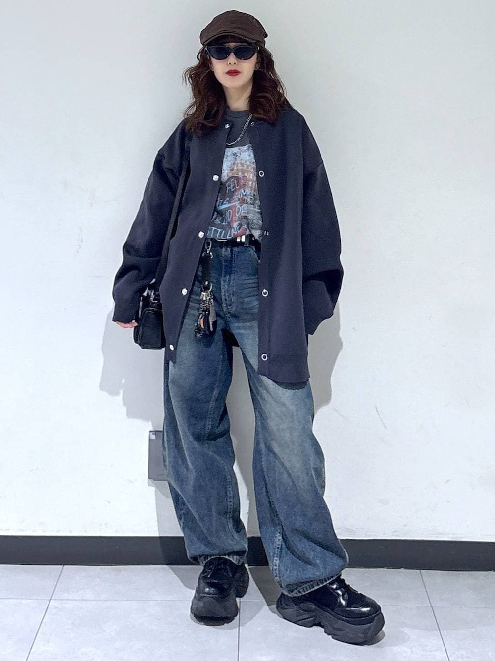 ブラック系のブーツ、ブルー系のデニムパンツ、ブラック系のショルダーバッグを着用したレディースの春コーディネートの1枚目の写真