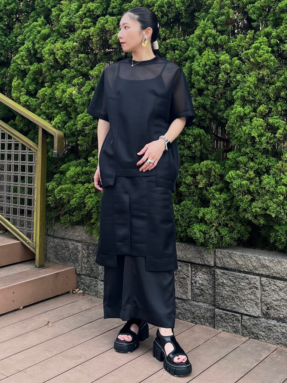 ブラック系のTシャツ/カットソー、ブラック系のスカート、ブラック系のサンダルを着用したレディースの春コーディネートの1枚目の写真