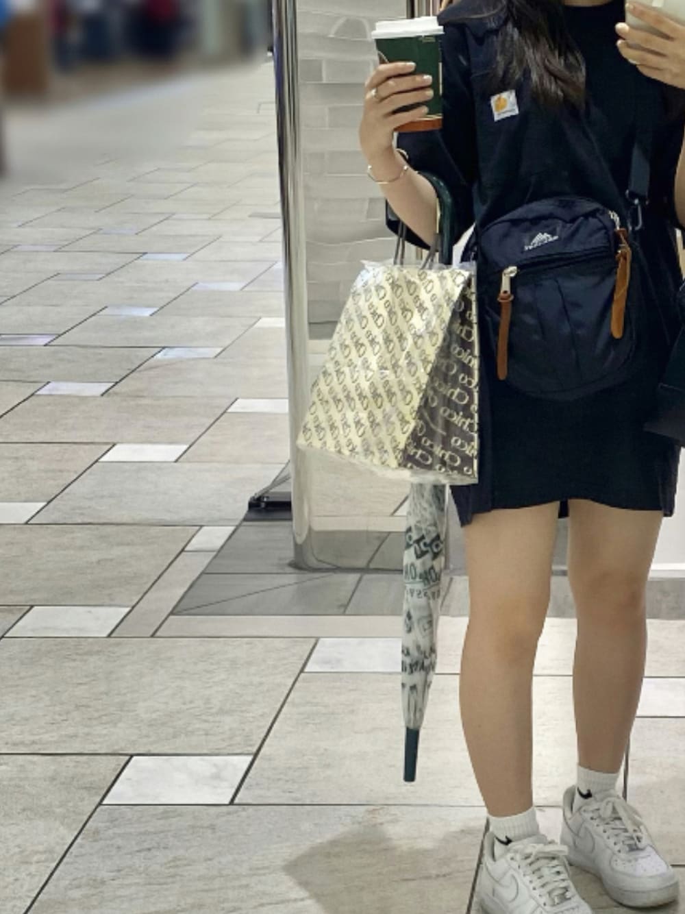 ブラック系のショルダーバッグ、ブラック系のTシャツ/カットソー、ホワイト系のスニーカーを着用したレディースの夏コーディネートの1枚目の写真