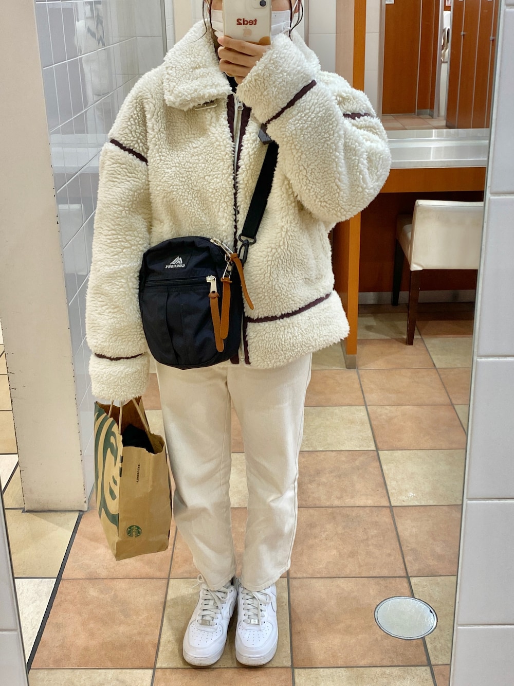 ホワイト系のスニーカー、ホワイト系のデニムパンツ、ブラック系のショルダーバッグを着用したレディースの冬コーディネートの1枚目の写真