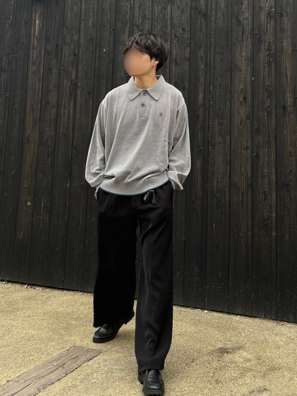 ブラック系のスラックス、ブラック系のドレスシューズ、グレー系のポロシャツを着用したメンズの秋コーディネートの1枚目の写真