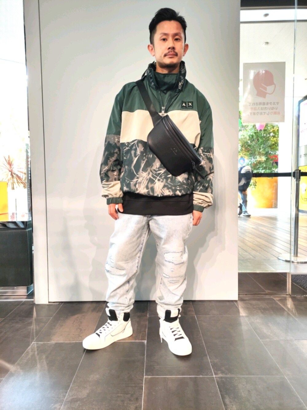 グリーン系のナイロンジャケット、ブラック系のスウェット、ブルー系のデニムパンツを着用したメンズの春コーディネートの1枚目の写真