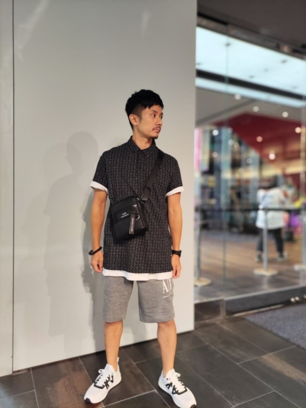 ブラック系のポロシャツ、ブラック系のショルダーバッグ、グレー系のスウェットパンツを着用したメンズの夏コーディネートの1枚目の写真