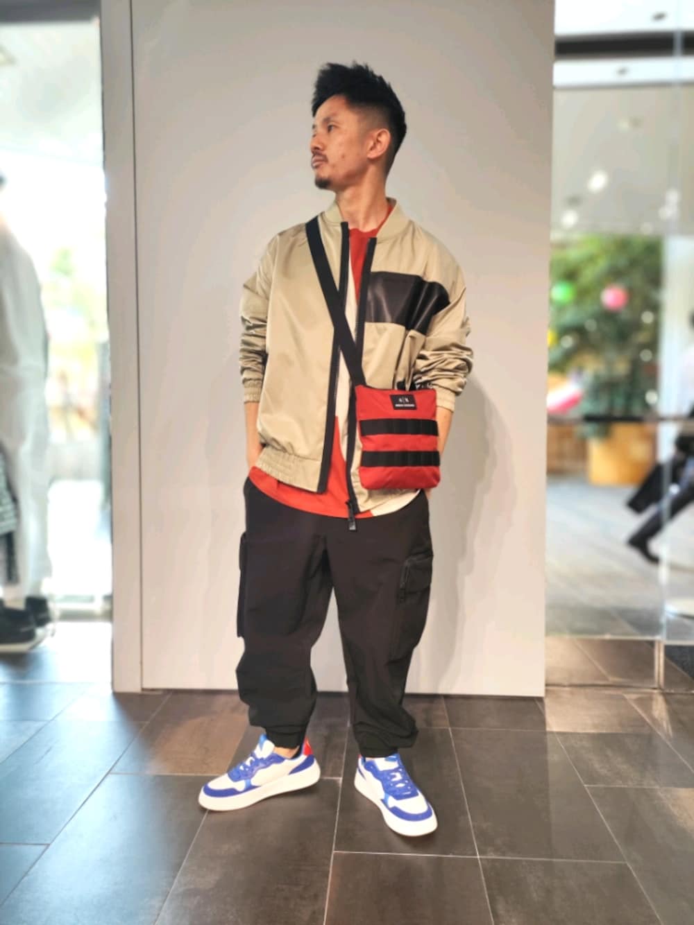 グレー系のブルゾン、レッド系のショルダーバッグ、ベージュ系のTシャツ/カットソーを着用したメンズの春コーディネートの1枚目の写真