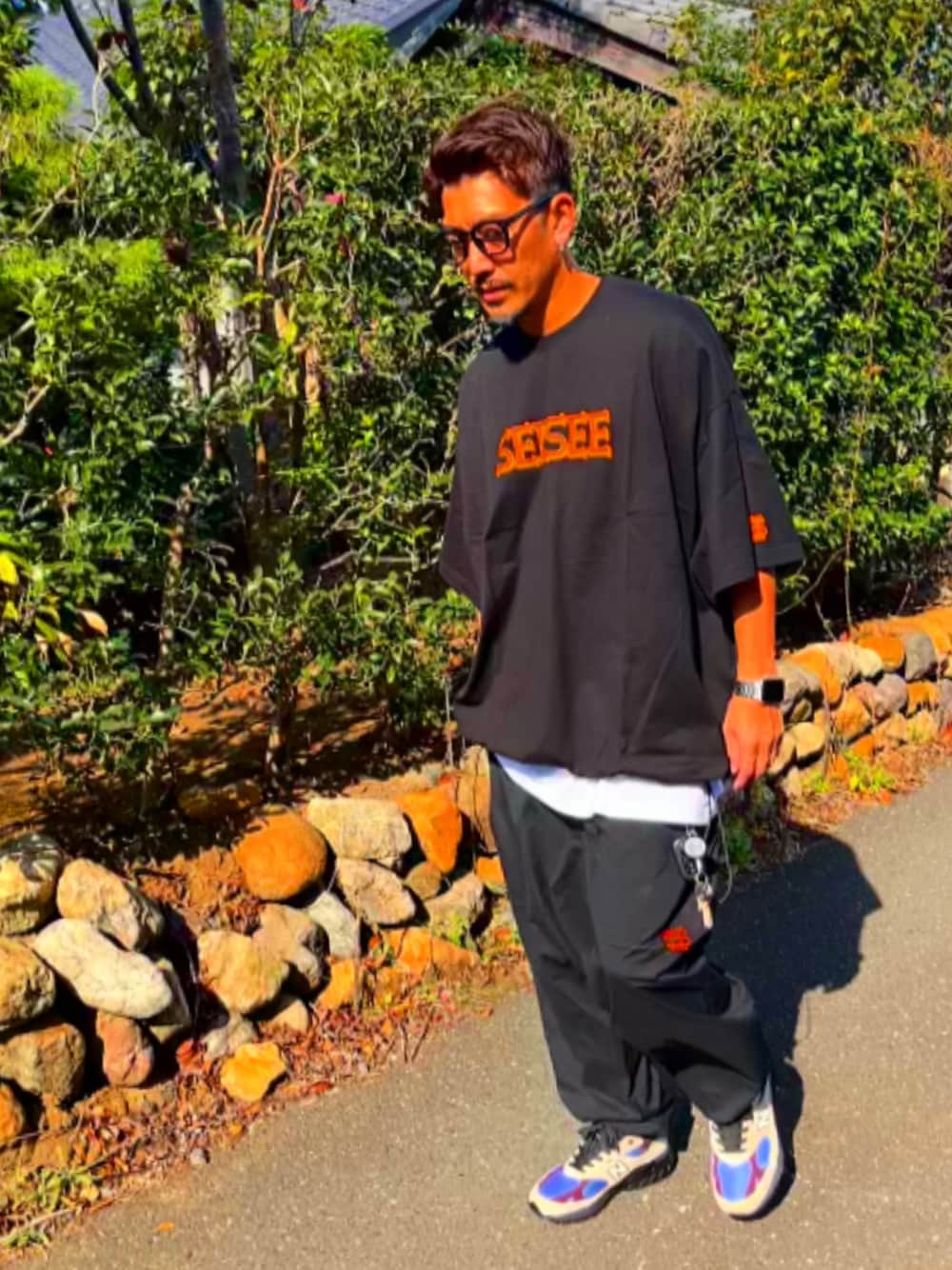 ブラック系のTシャツ/カットソー、ブラック系のその他パンツ、ホワイト系のスニーカーを着用したメンズの秋コーディネートの1枚目の写真