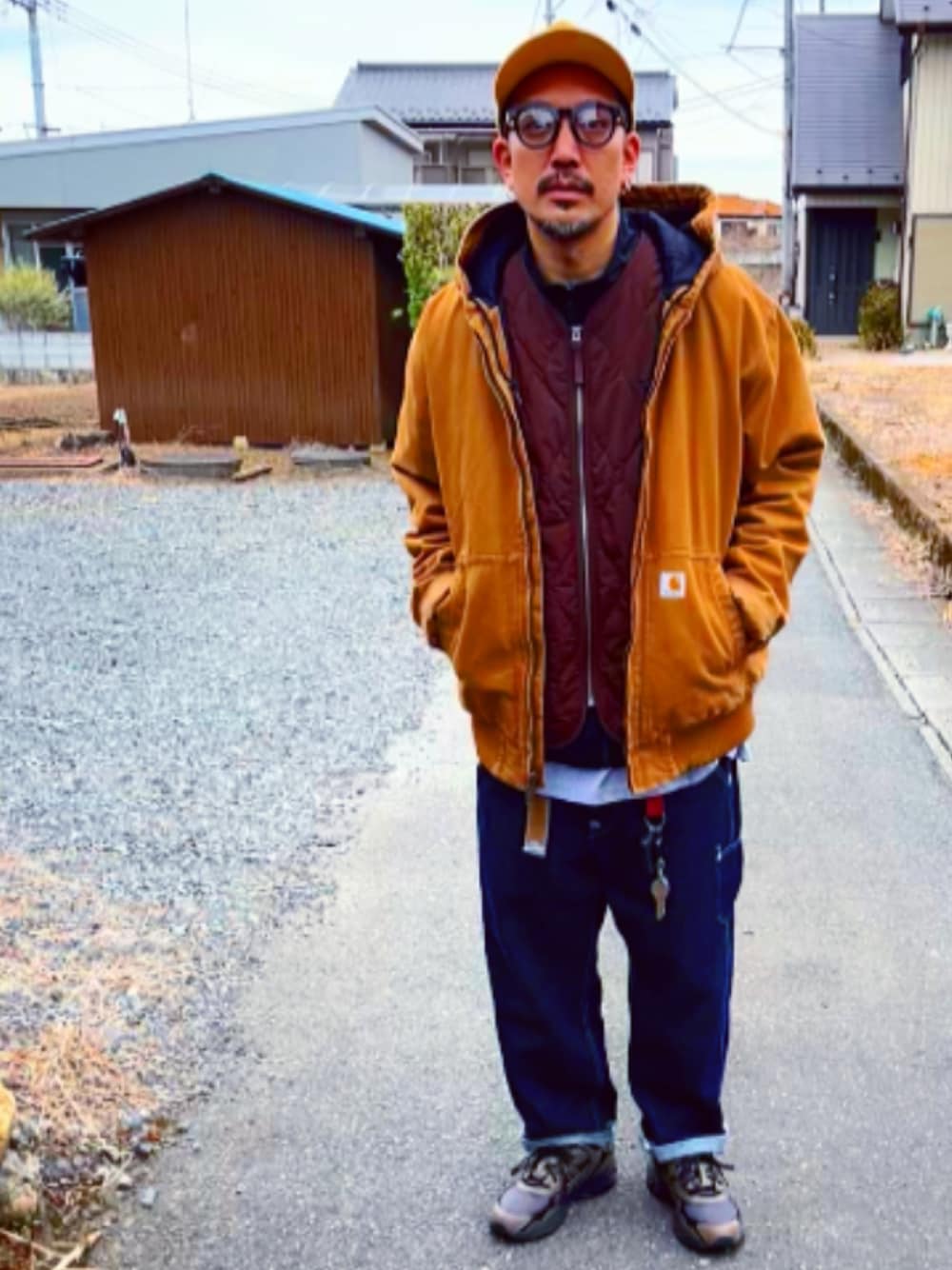 ブラウン系のベスト、ブラック系のナイロンジャケット、ブラウン系のブルゾンを着用したメンズの冬コーディネートの1枚目の写真