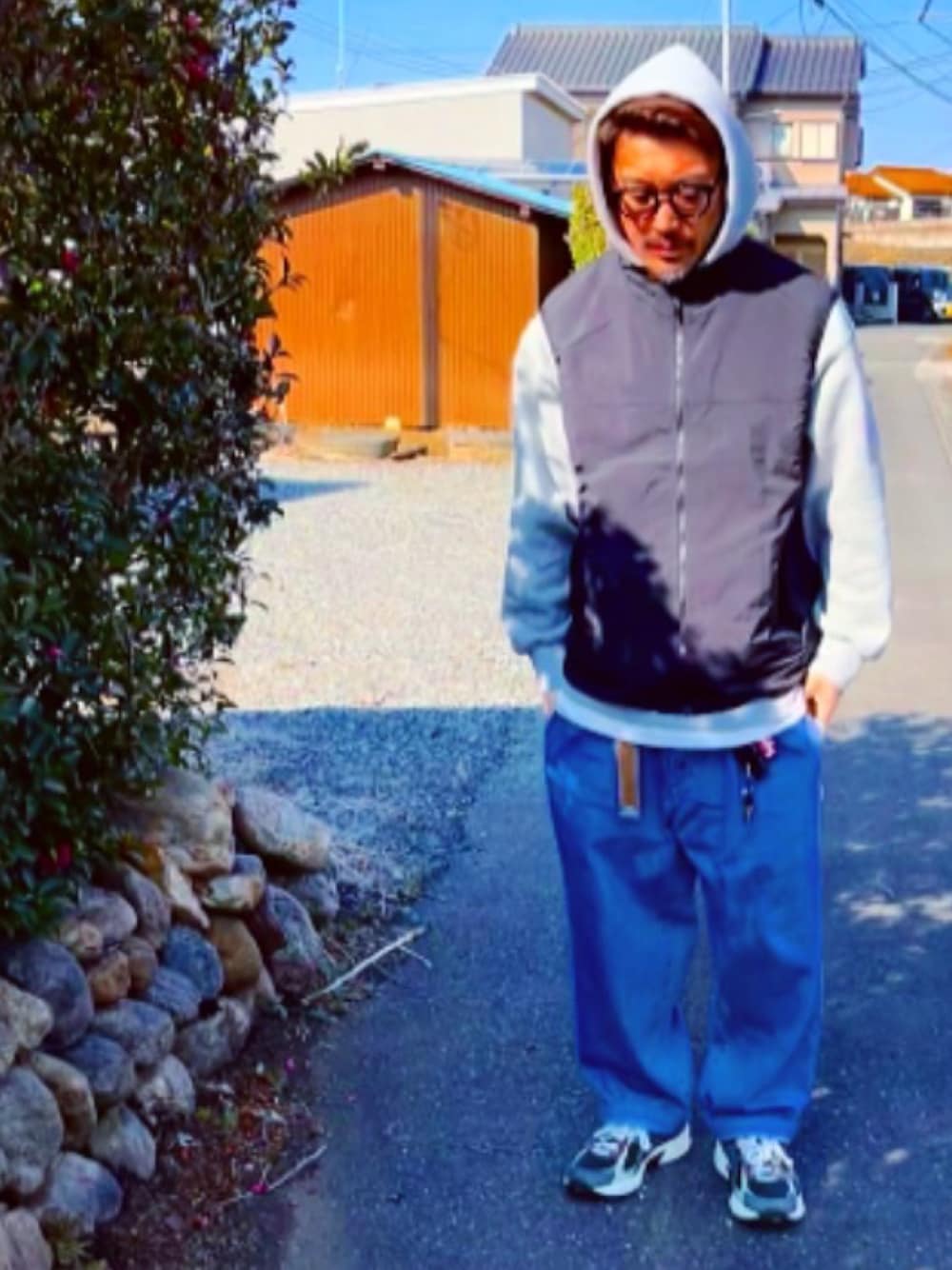 グレー系のパーカー、ブラック系のダウンベスト、ブルー系のデニムパンツを着用したメンズの冬コーディネートの1枚目の写真