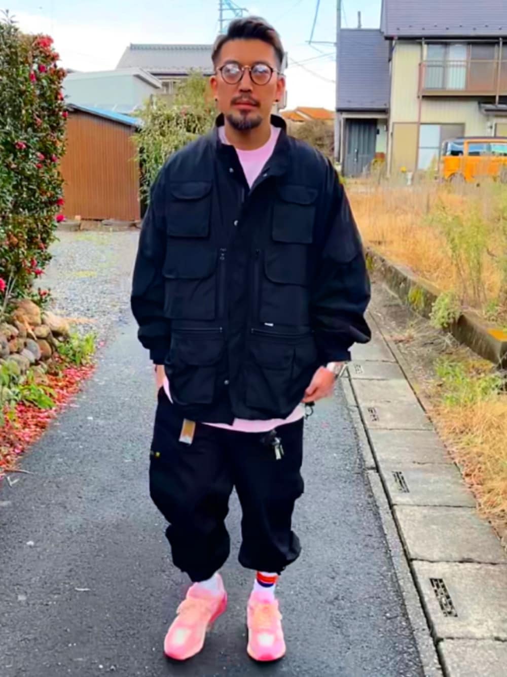 ブラック系のミリタリージャケット、ピンク系のTシャツ/カットソー、ブラック系のカーゴパンツを着用したメンズの冬コーディネートの1枚目の写真