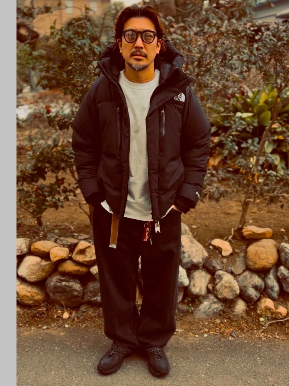 ブラック系のTシャツ/カットソー、ブラック系のダウンジャケット/コート、ブラック系のデニムパンツを着用したメンズの春コーディネートの1枚目の写真