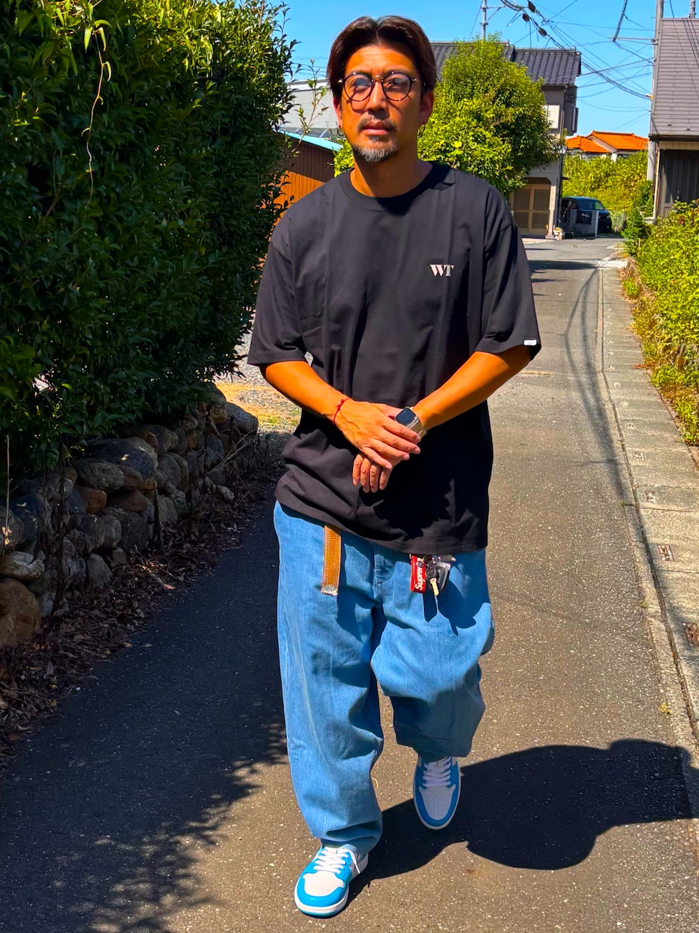 ブラック系のTシャツ/カットソー、ブルー系のデニムパンツ、ブルー系のスニーカーを着用したメンズの秋コーディネートの1枚目の写真