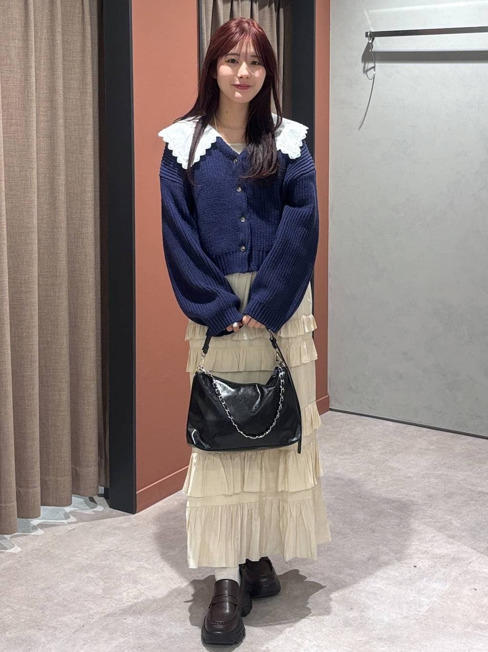 ブラック系のショルダーバッグ、ブラウン系のローファー、ホワイト系のスカートを着用したレディースの冬コーディネートの1枚目の写真