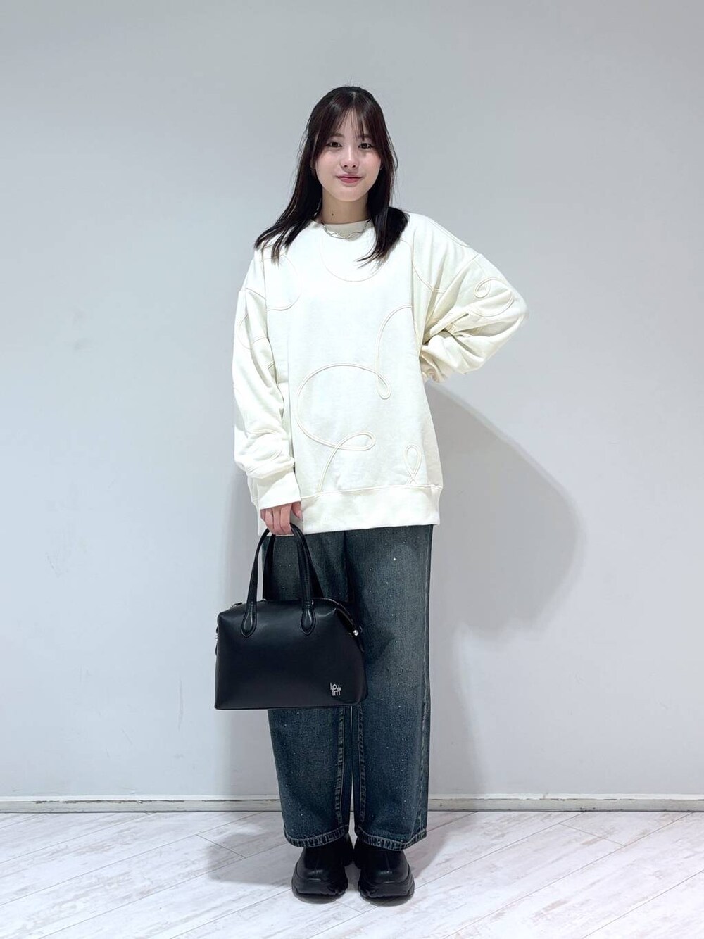 ブラック系のブーツ、ブルー系のデニムパンツ、ブラック系のショルダーバッグを着用したレディースの冬コーディネートの1枚目の写真