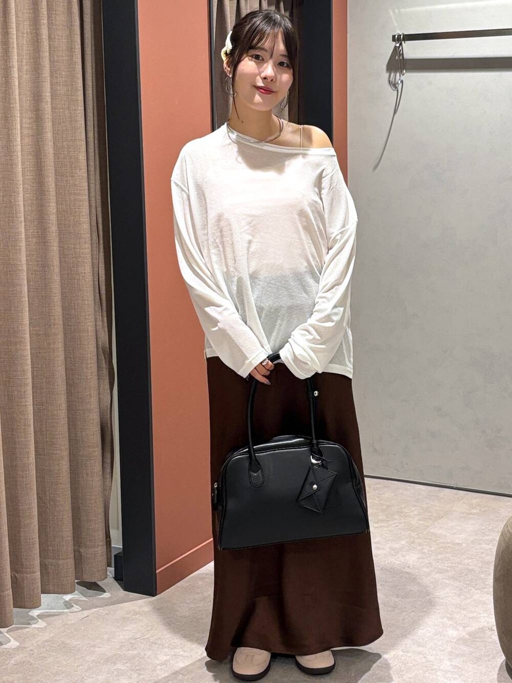 ブラウン系のスカート、ピンク系のスニーカー、ブラック系のボストンバッグを着用したレディースの秋コーディネートの1枚目の写真