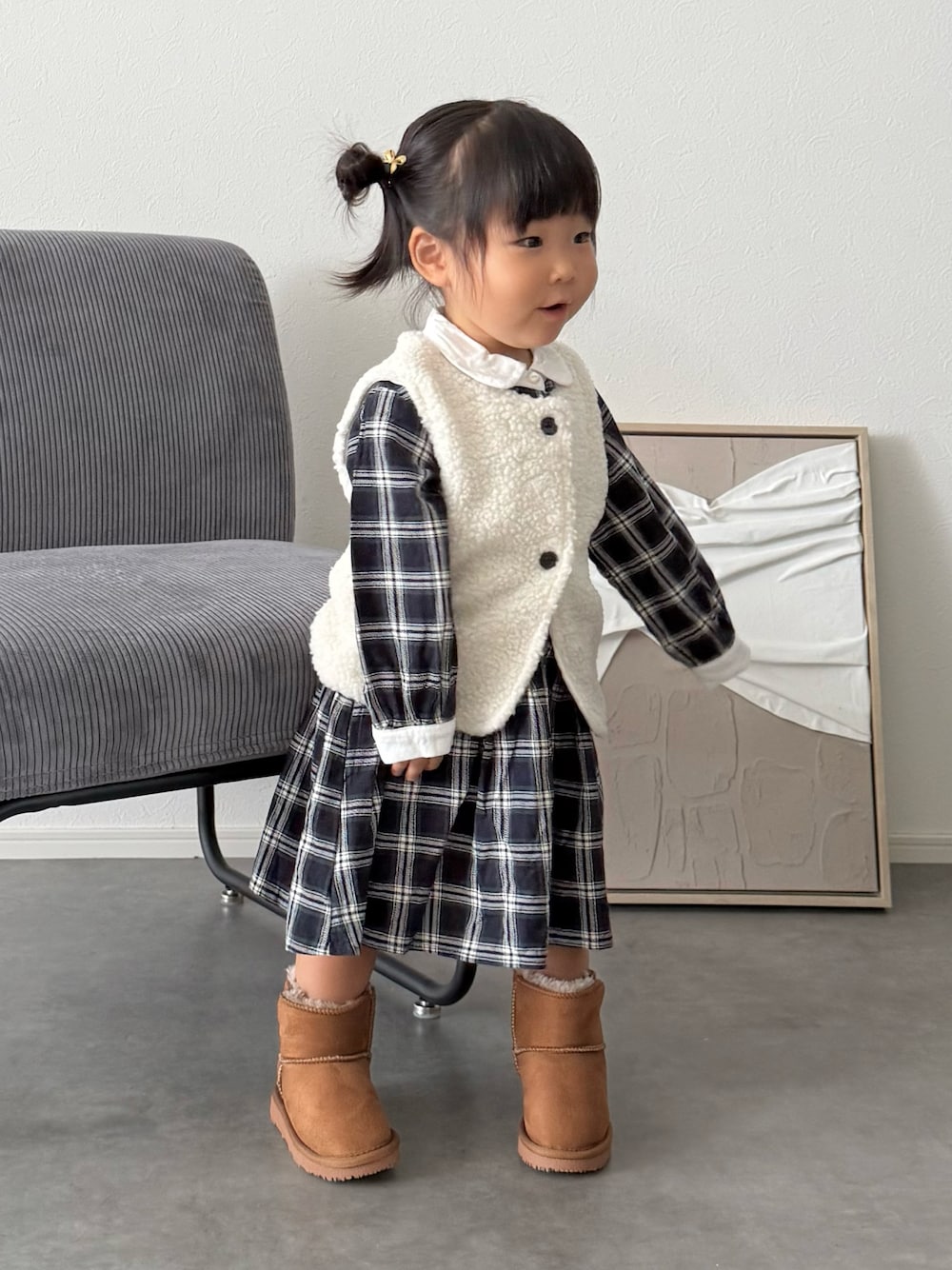 ブルー系のシャツワンピース、イエロー系のブーツ、ホワイト系のベストを着用したキッズの秋コーディネートの1枚目の写真