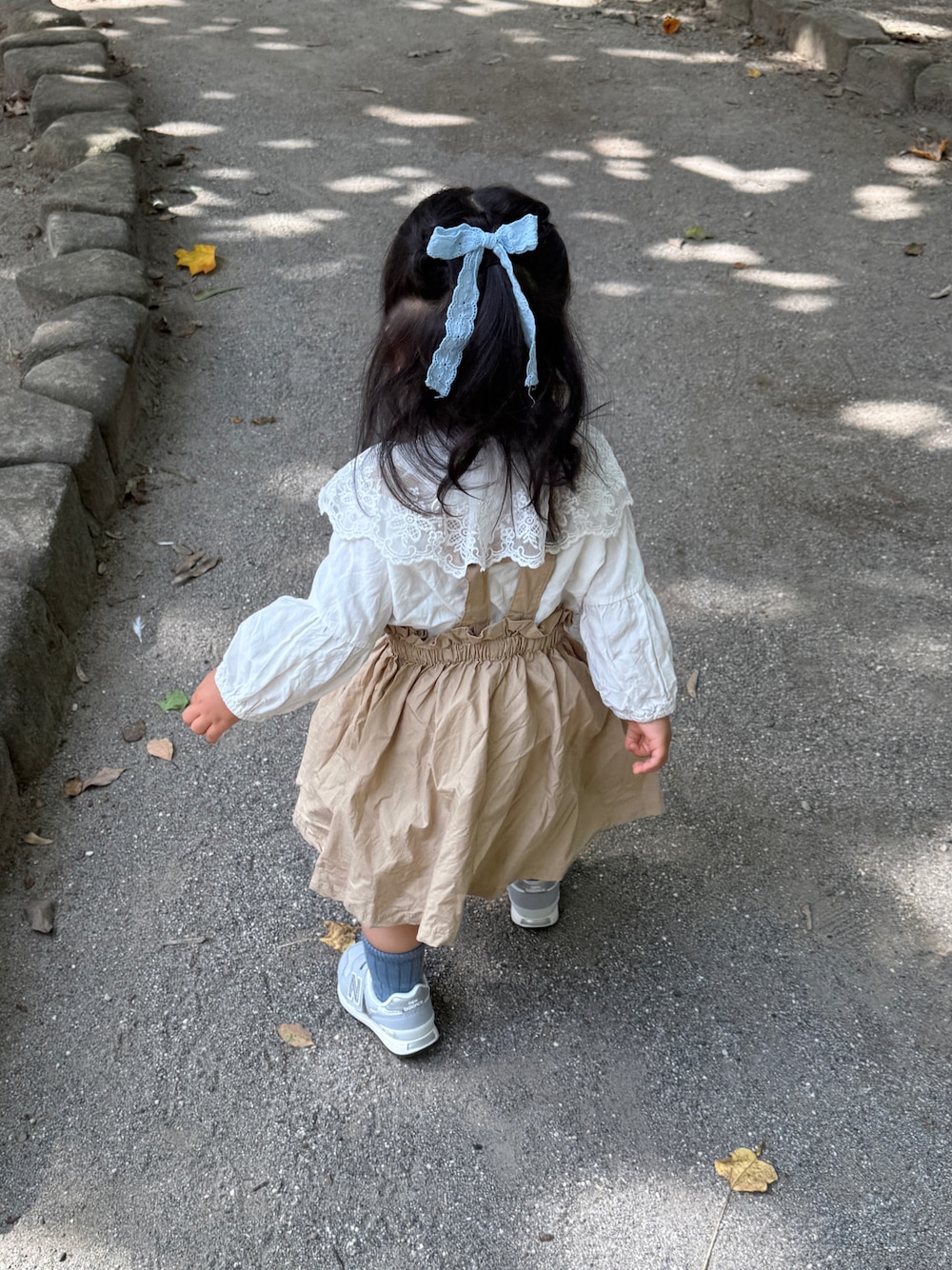 グレー系のスニーカー、ベージュ系のワンピース/ドレスを着用したキッズの秋コーディネートの1枚目の写真