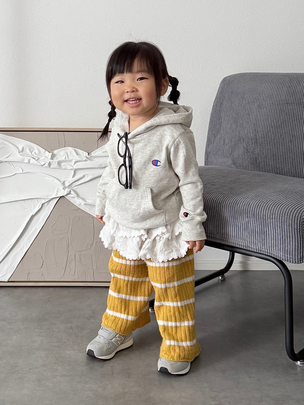 ホワイト系のスカート、グレー系のスニーカー、グレー系のパーカーを着用したキッズの秋コーディネートの1枚目の写真
