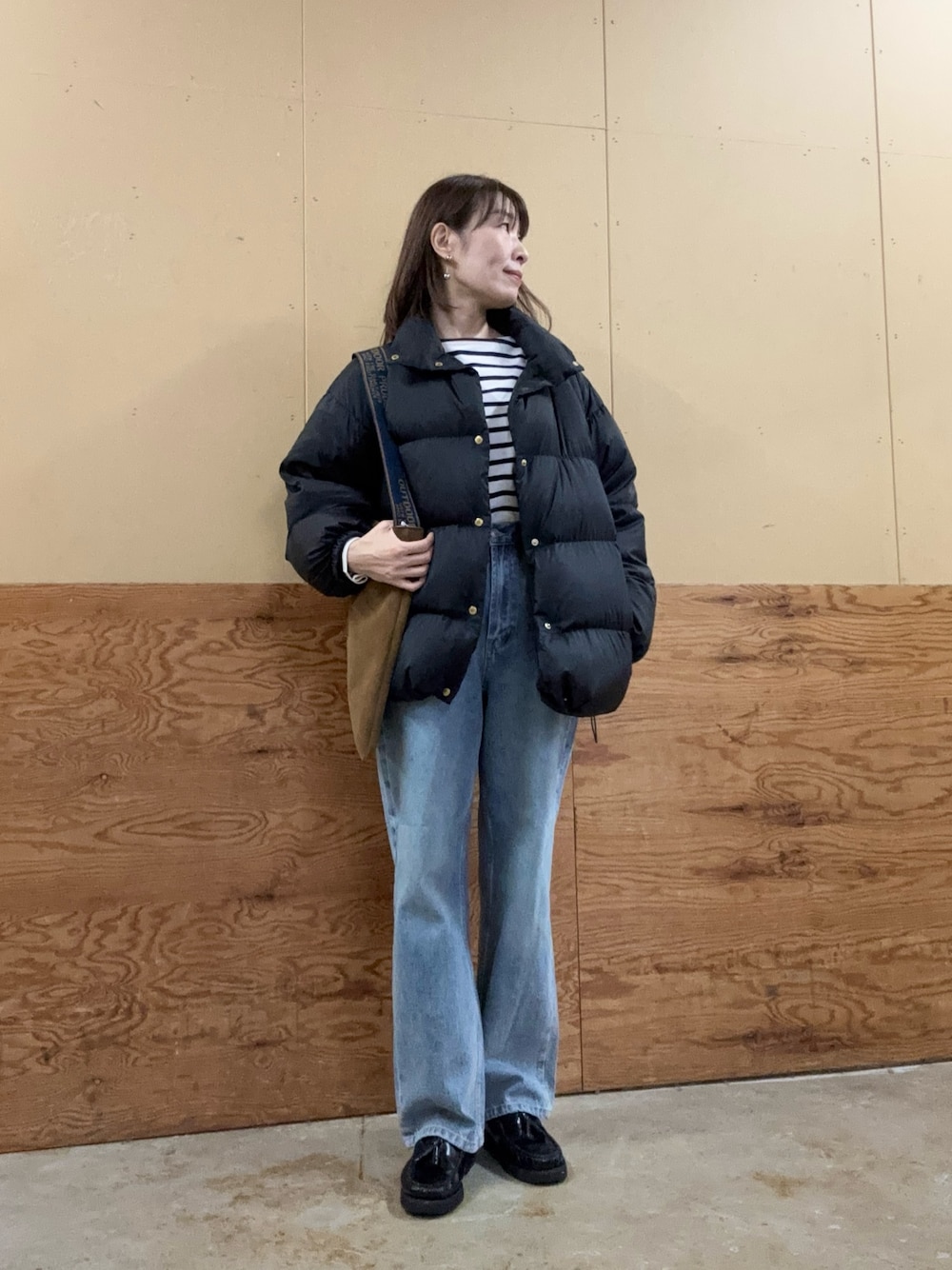 イエロー系のショルダーバッグ、ブルー系のデニムパンツ、ブラック系のダウンジャケット/コートを着用したレディースの秋コーディネートの1枚目の写真