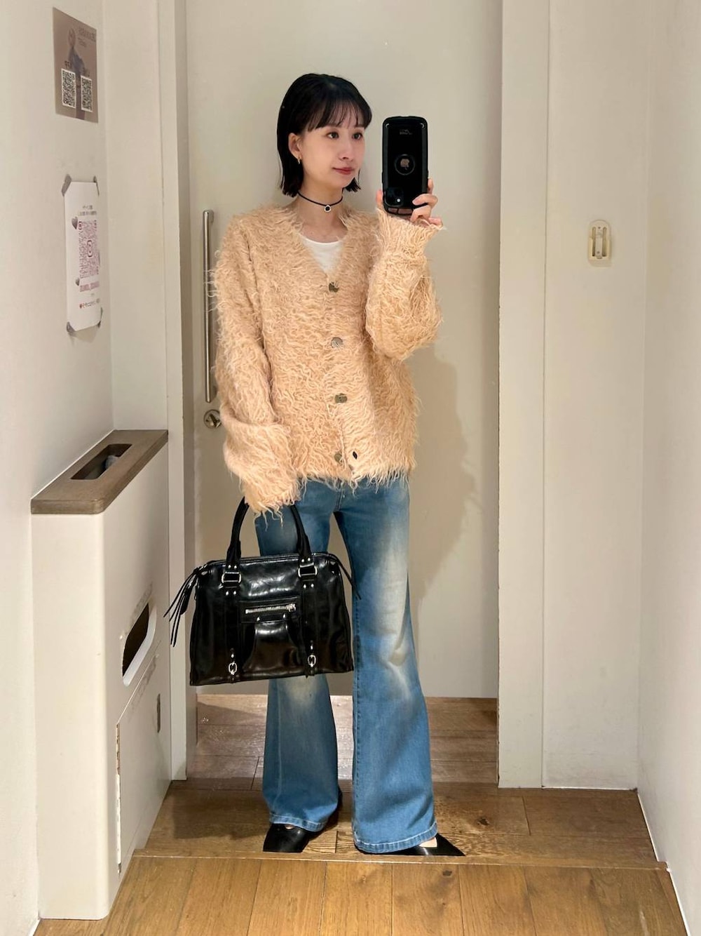 ブラック系のボストンバッグ、ブルー系のデニムパンツ、オレンジ系のカーディガン/ボレロを着用したレディースの冬コーディネートの1枚目の写真