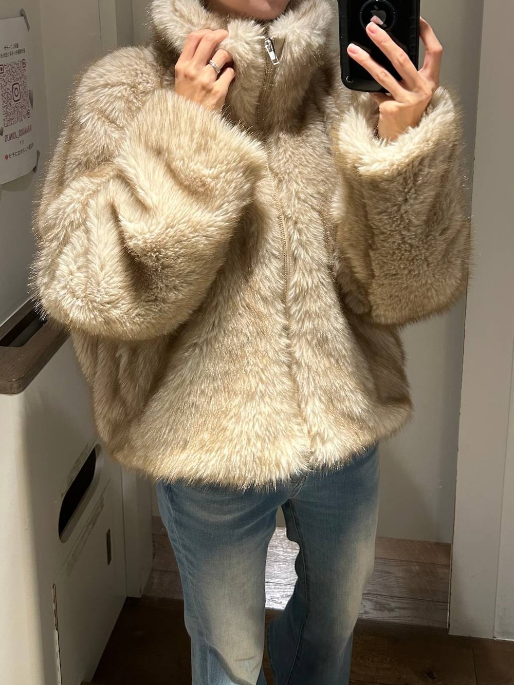 ベージュ系のブルゾン、ブルー系のデニムパンツ、ブラック系のチョーカーを着用したレディースの冬コーディネートの1枚目の写真