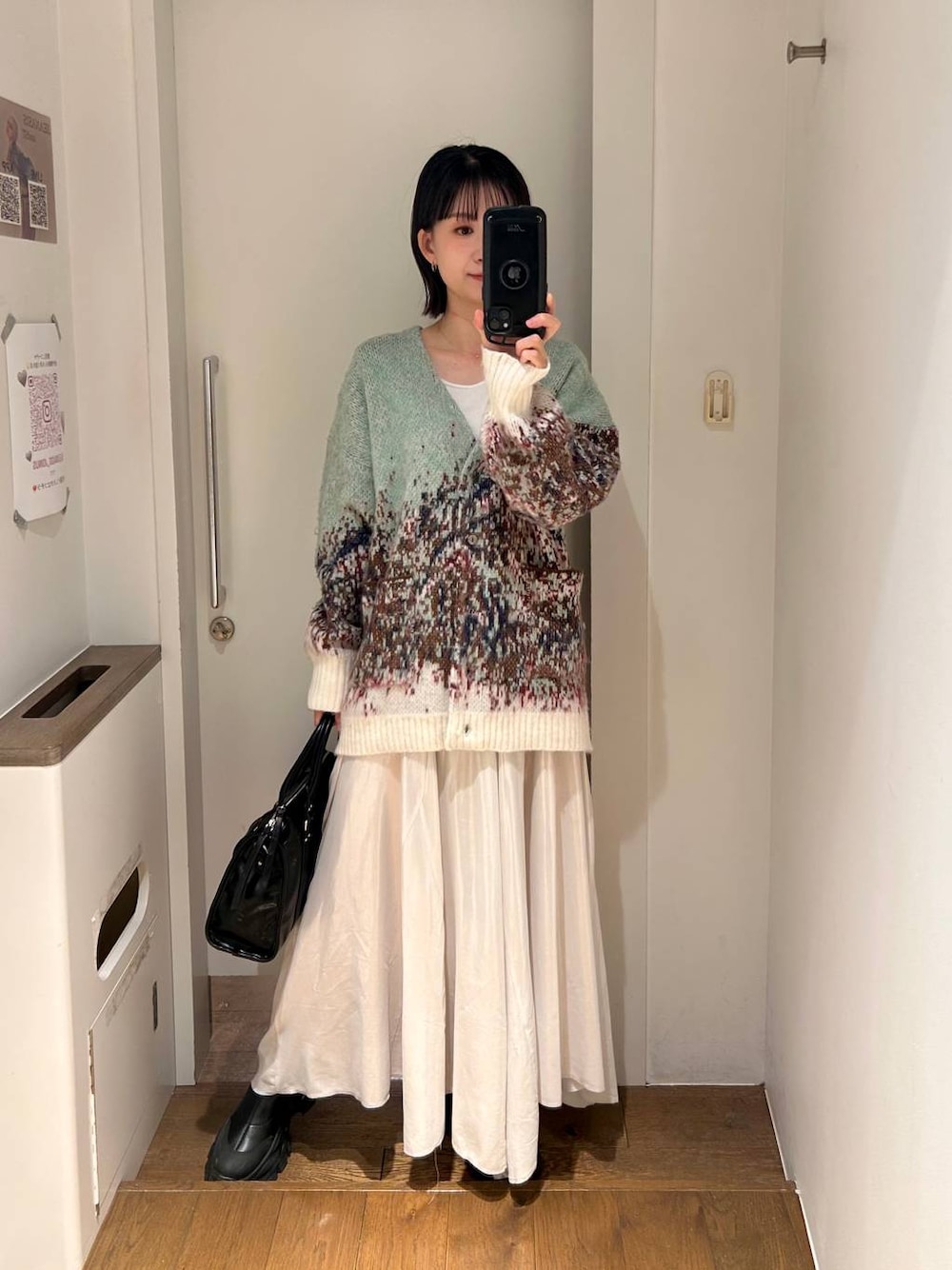 ブラック系のトートバッグ、ブラック系のブーツ、ホワイト系のスカートを着用したレディースの秋コーディネートの1枚目の写真