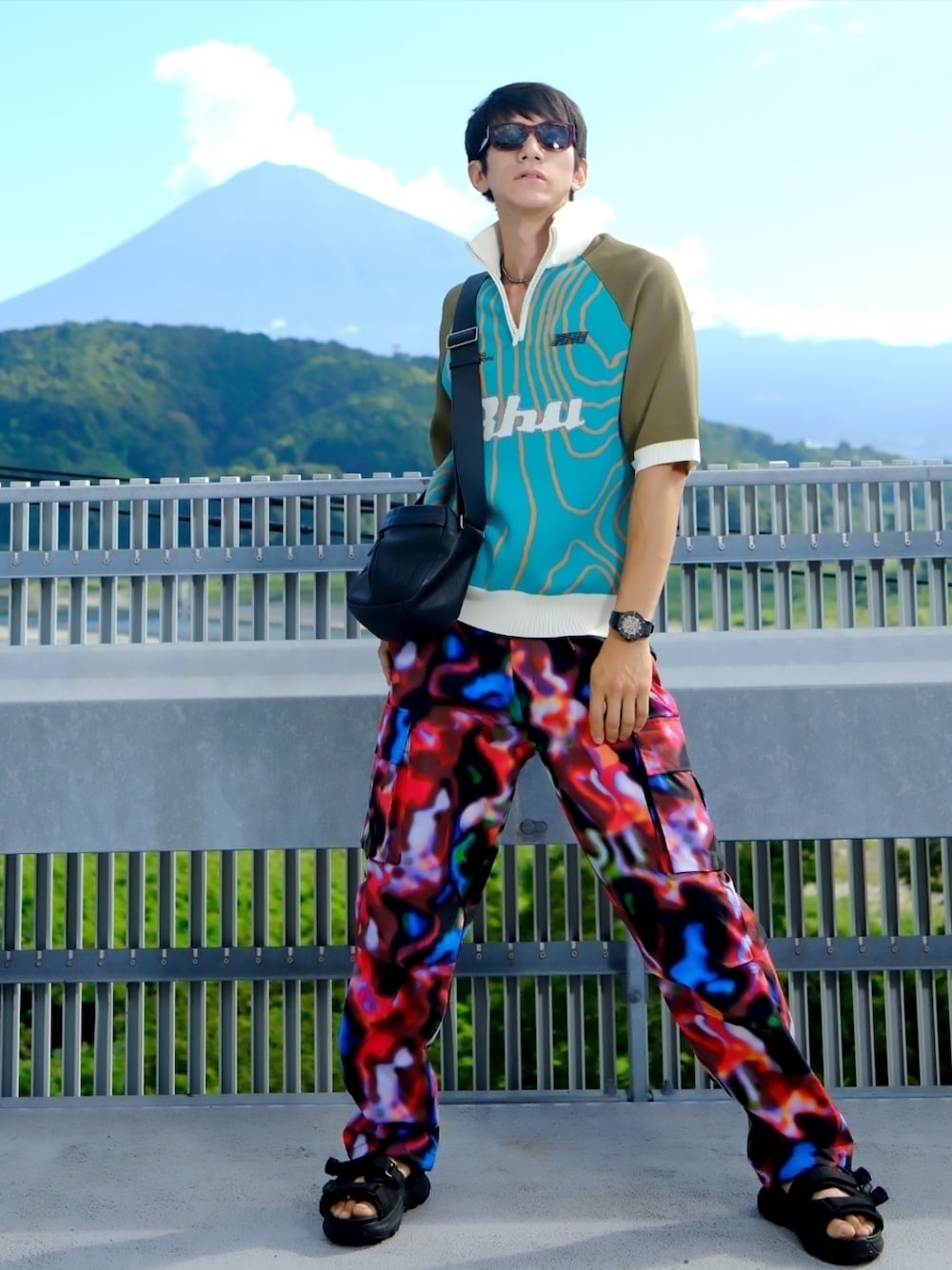 グリーン系のTシャツ/カットソー、ブラック系のメッセンジャーバッグ、その他のカーゴパンツを着用したメンズの夏コーディネートの1枚目の写真