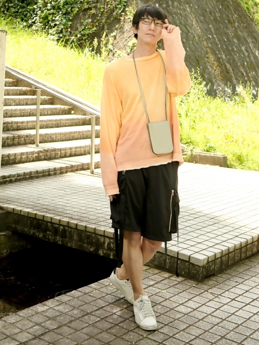 オレンジ系のニット/セーター、ブラック系のその他パンツ、ホワイト系のスニーカーを着用したメンズの夏コーディネートの1枚目の写真