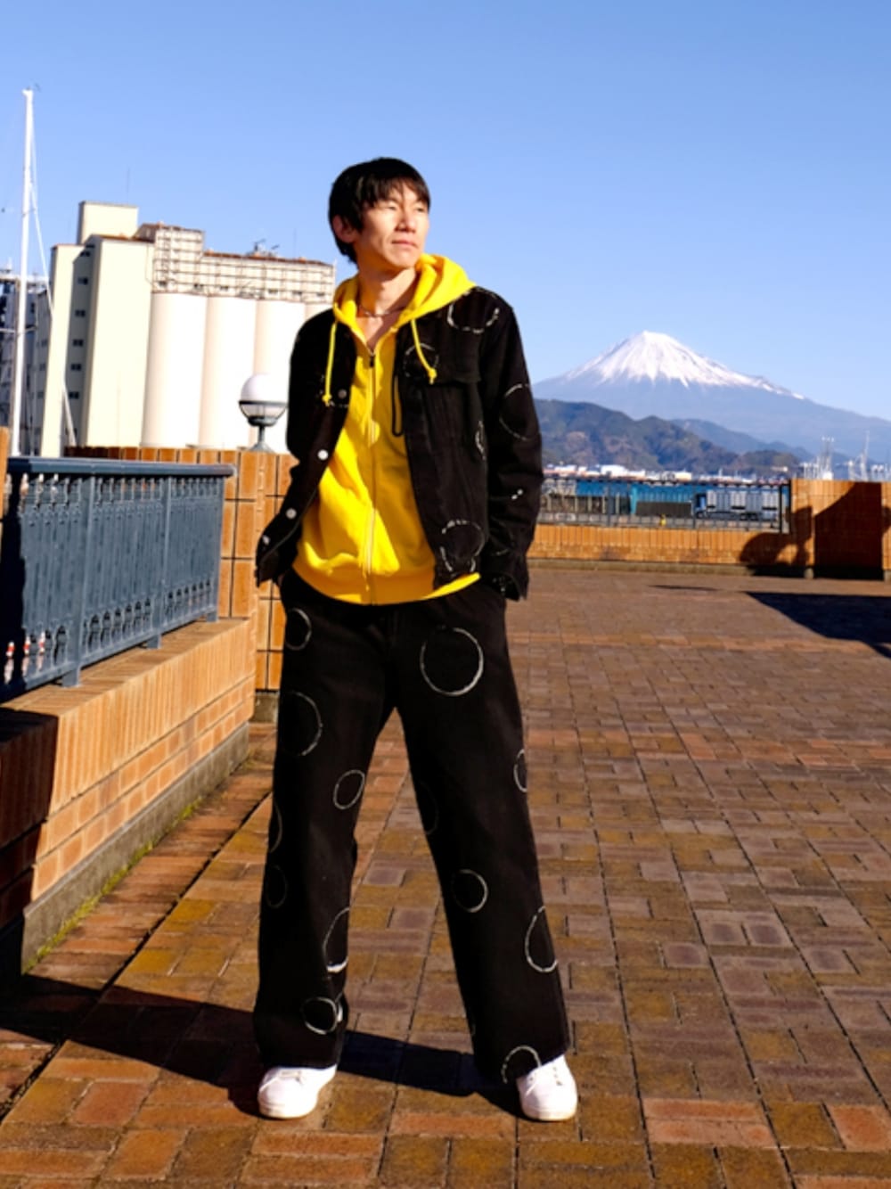 ブルー系のデニムパンツ、ブラック系のデニムジャケット、イエロー系のパーカーを着用したメンズの冬コーディネートの1枚目の写真