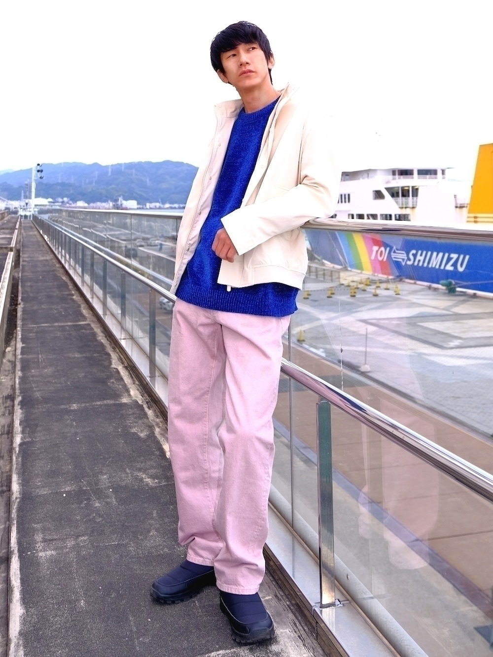 ピンク系のデニムパンツ、ブルー系のTシャツ/カットソー、ベージュ系のカバーオールを着用したメンズの冬コーディネートの1枚目の写真