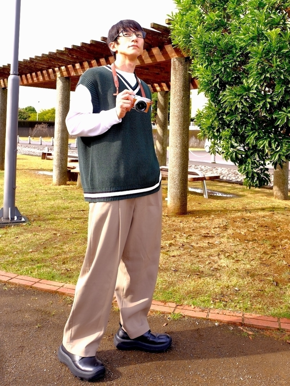 ホワイト系のTシャツ/カットソー、グリーン系のベスト、ブラック系のドレスシューズを着用したメンズの秋コーディネートの1枚目の写真