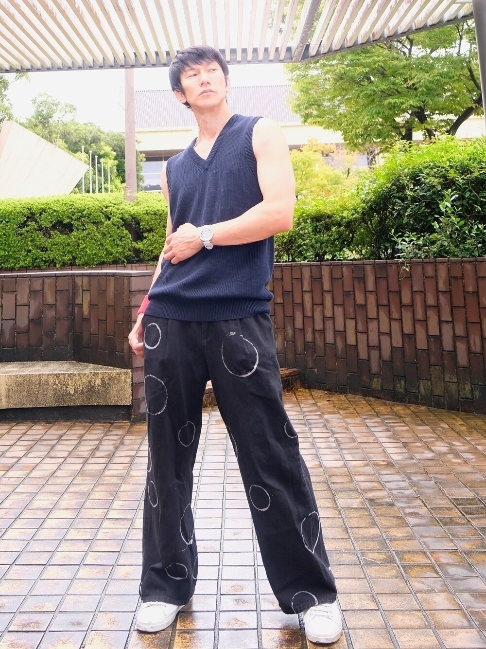 ブルー系のベスト、ブルー系のデニムパンツ、ホワイト系のスニーカーを着用したメンズの秋コーディネートの1枚目の写真