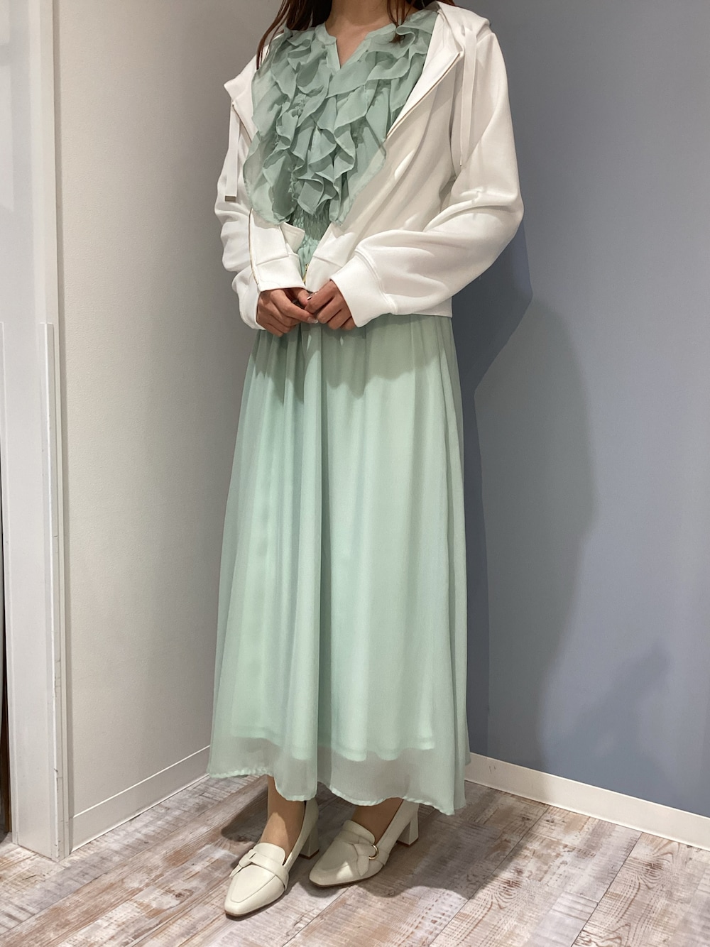 ホワイト系のパーカー、グリーン系のワンピース、ベージュ系のパンプスを着用したレディースの春コーディネートの1枚目の写真