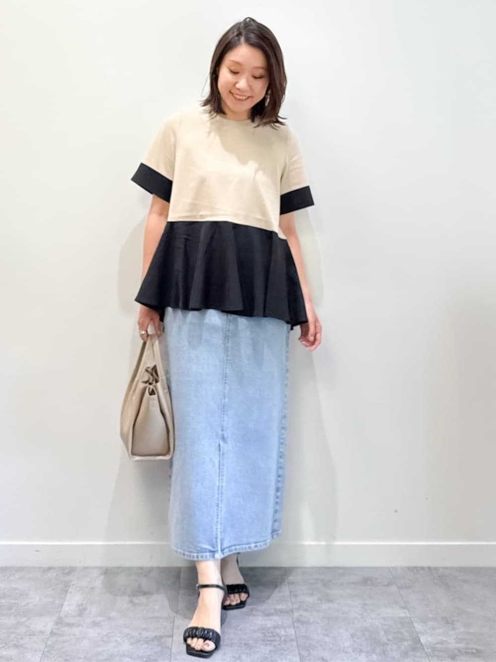 ベージュ系のTシャツ/カットソー、ブルー系のデニムスカート、ベージュ系のショルダーバッグを着用したレディースの夏コーディネートの1枚目の写真
