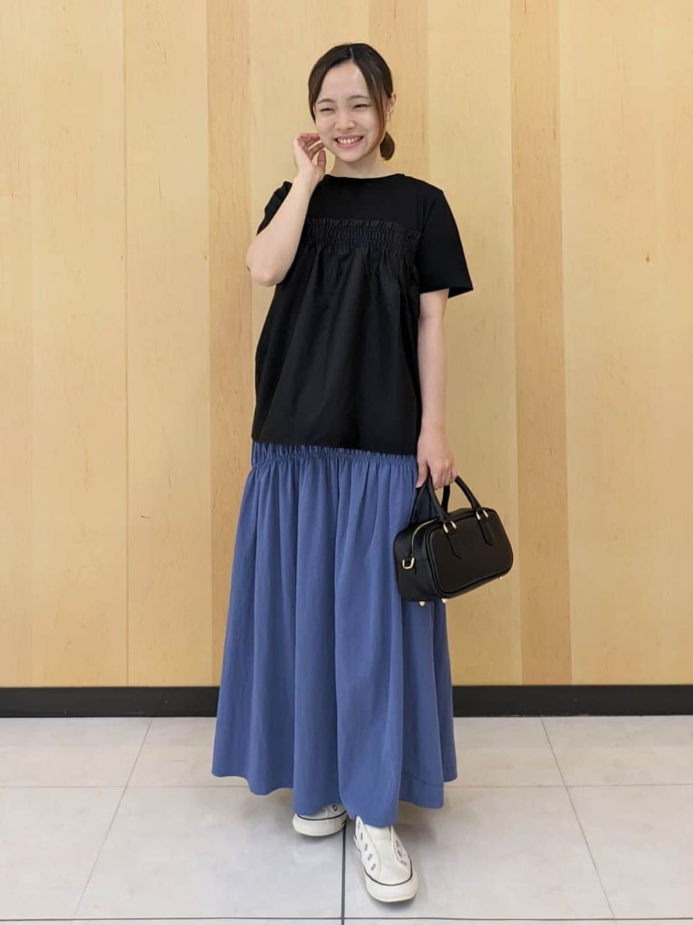 ブラック系のTシャツ/カットソー、ブルー系のスカート、ブラック系のショルダーバッグを着用したレディースの秋コーディネートの1枚目の写真