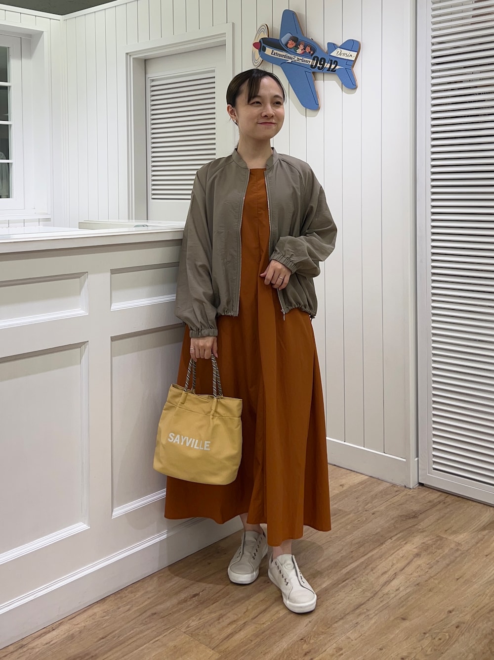 グリーン系のブルゾン、イエロー系のワンピース、イエロー系のトートバッグを着用したレディースの夏コーディネートの1枚目の写真