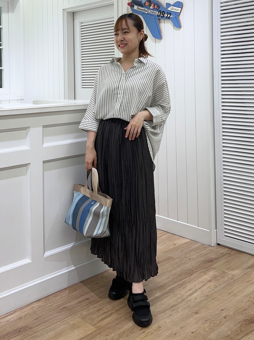 ホワイト系のシャツ/ブラウス、グレー系のスカート、ブラック系のサンダルを着用したレディースの春コーディネートの1枚目の写真