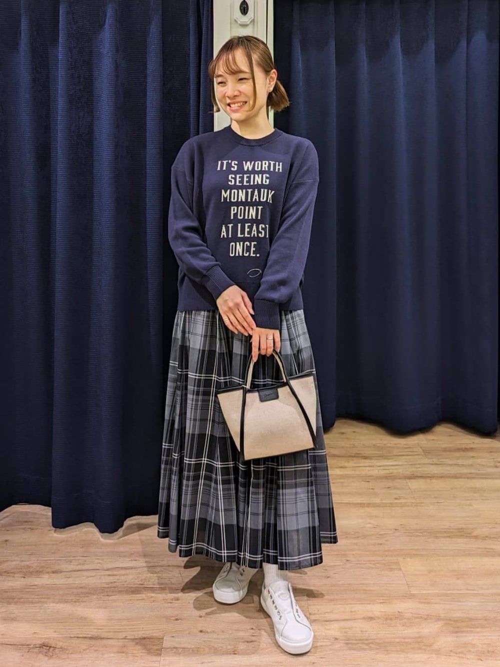 ブルー系のニット/セーター、グリーン系のスカート、ブラック系のショルダーバッグを着用したレディースの春コーディネートの1枚目の写真