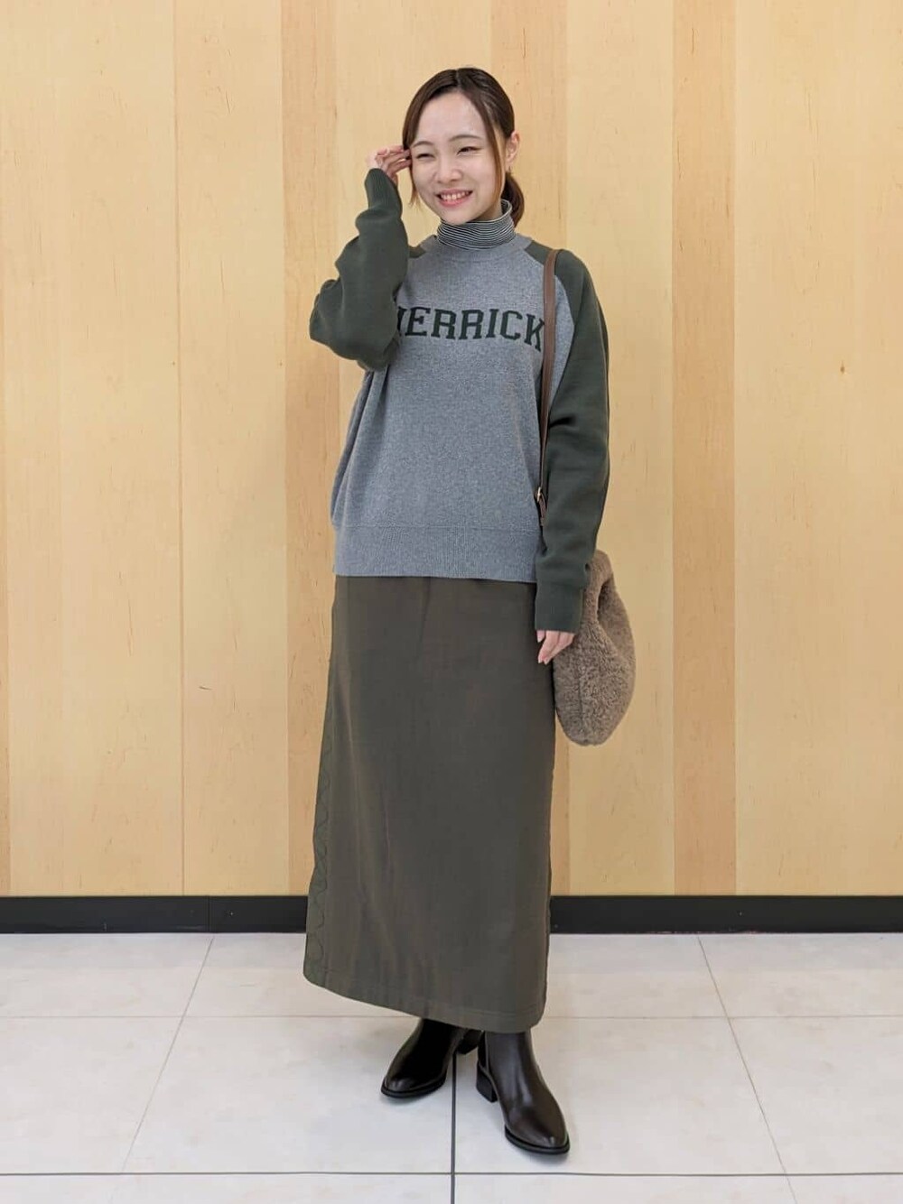 ブラック系のTシャツ/カットソー、グリーン系のニット/セーター、グリーン系のスカートを着用したレディースの秋コーディネートの1枚目の写真