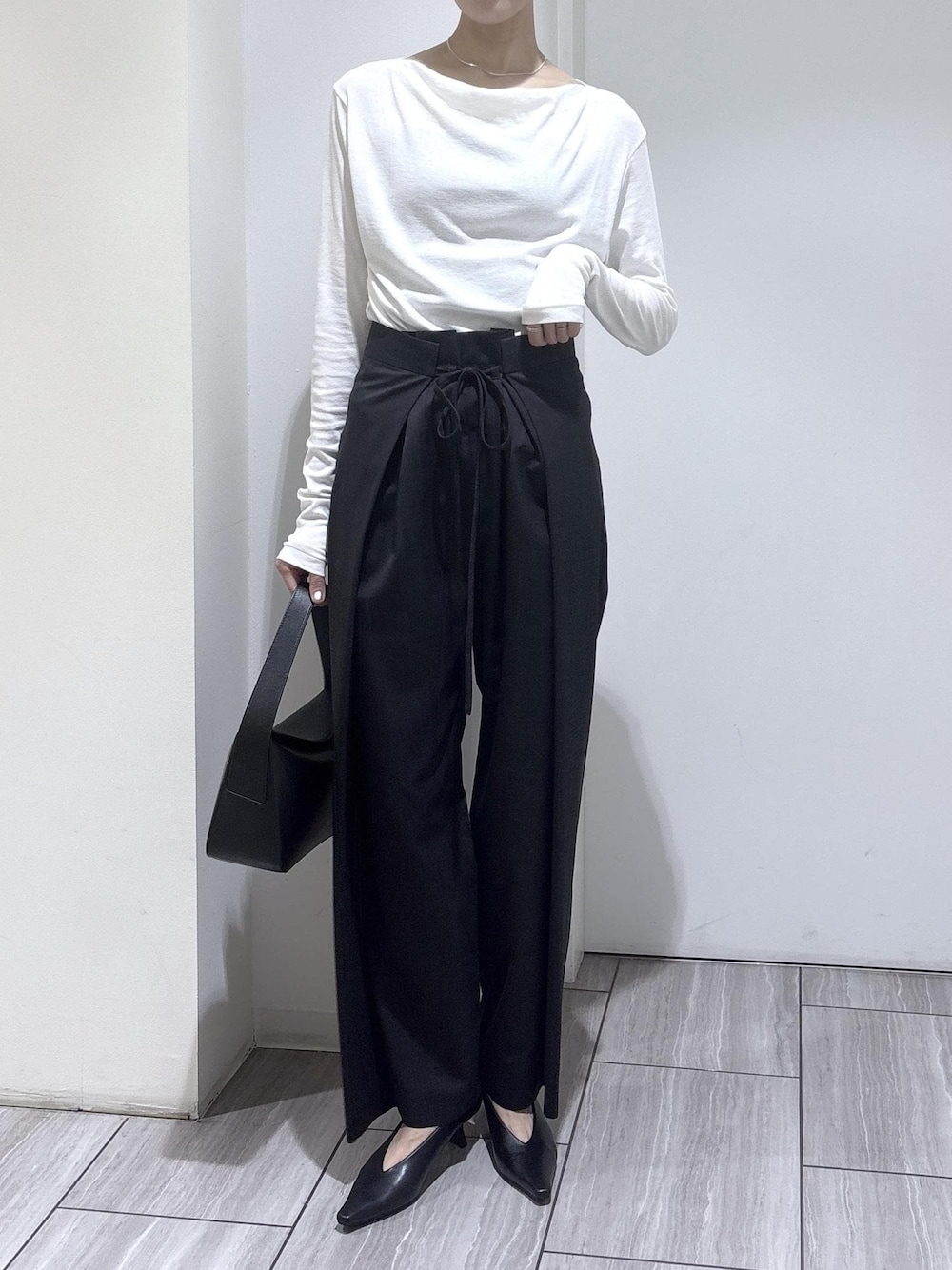 ブラック系のショルダーバッグ、ブラック系のパンプス、ホワイト系のTシャツ/カットソーを着用したレディースの夏コーディネートの1枚目の写真