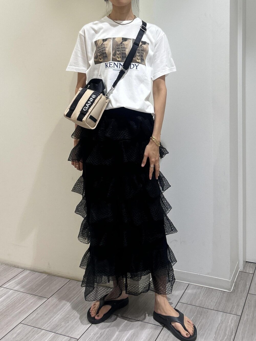 ブラック系のサンダル、ホワイト系のTシャツ/カットソー、ブラック系のスカートを着用したレディースの夏コーディネートの1枚目の写真
