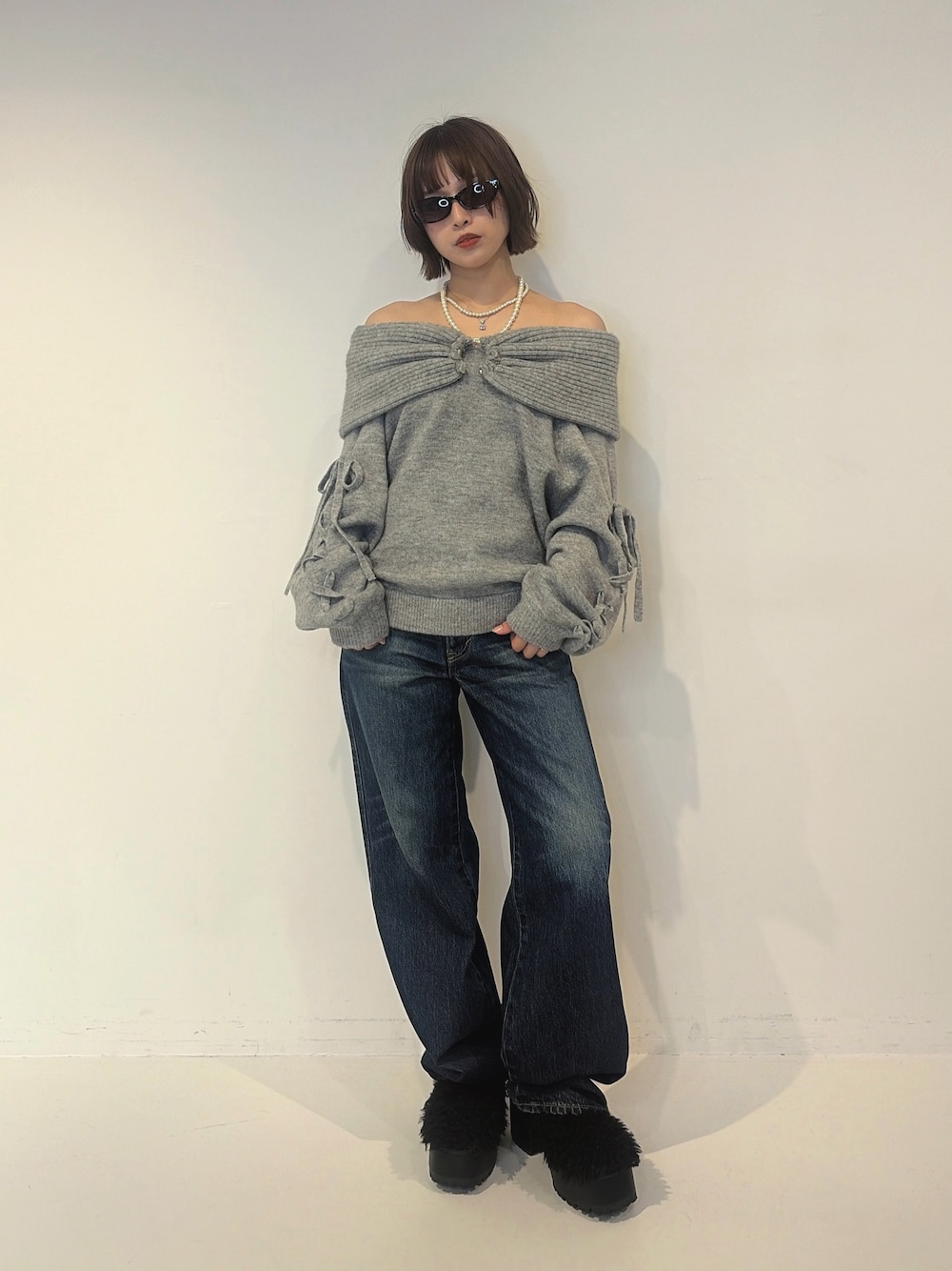 ブルー系のデニムパンツ、ブラック系のサンダル、グレー系のニット/セーターを着用したレディースの秋コーディネートの1枚目の写真
