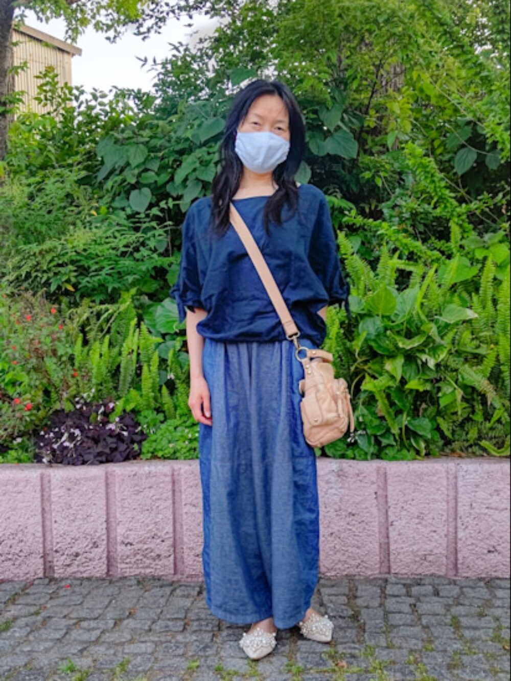 ベージュ系のシューズ、ブルー系のパンツ、ベージュ系のショルダーバッグを着用したレディースの春コーディネートの1枚目の写真