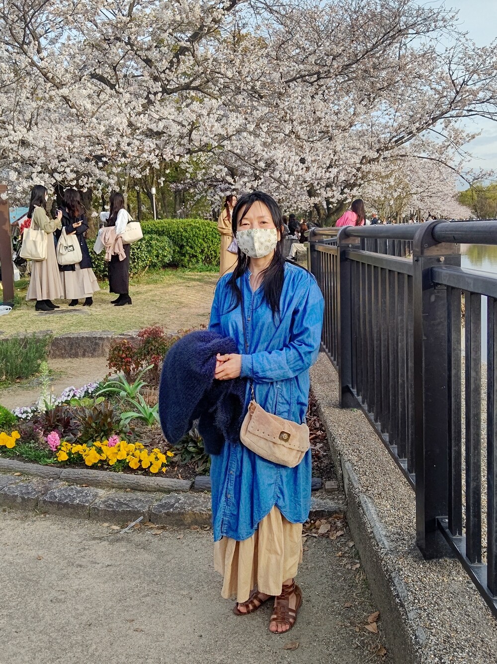 ブルー系のその他アウター、ブルー系のシャツワンピース、ベージュ系のスカートを着用したレディースの春コーディネートの2枚目の写真