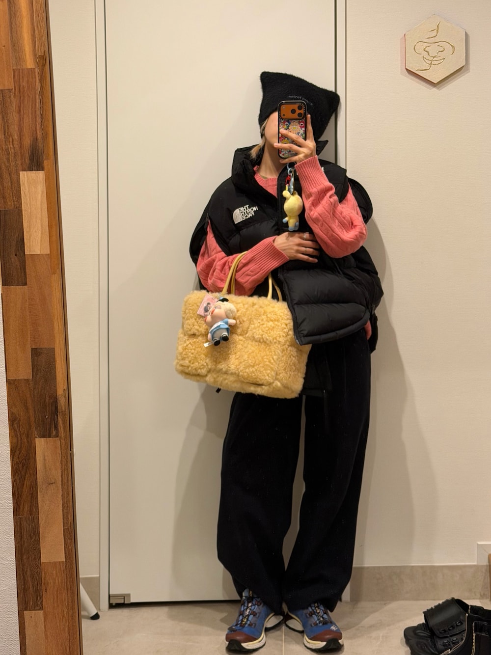 ブラック系のパンツ、ブラック系のダウンベスト、イエロー系のハンドバッグを着用したレディースの秋コーディネートの1枚目の写真