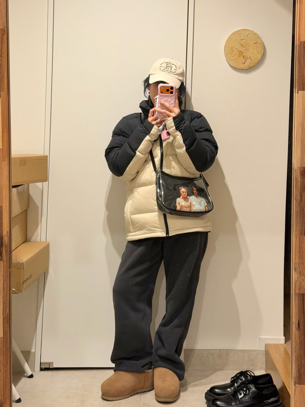 グレー系のパンツ、ホワイト系のダウンジャケット/コート、ブラック系のバッグを着用したレディースの冬コーディネートの1枚目の写真