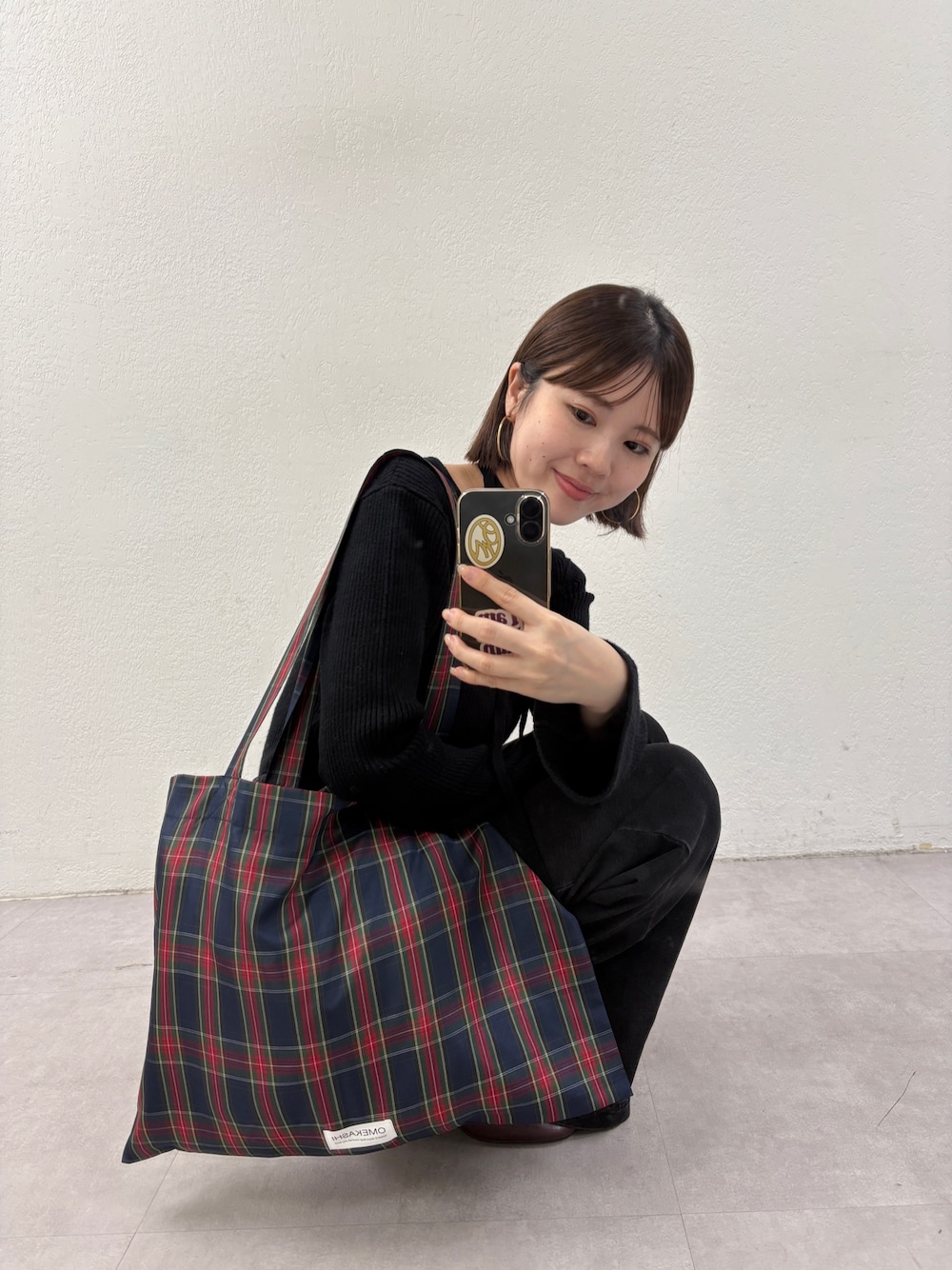 ブラック系のニット/セーター、グリーン系のトートバッグ、グレー系のデニムパンツを着用したレディースの秋コーディネートの1枚目の写真