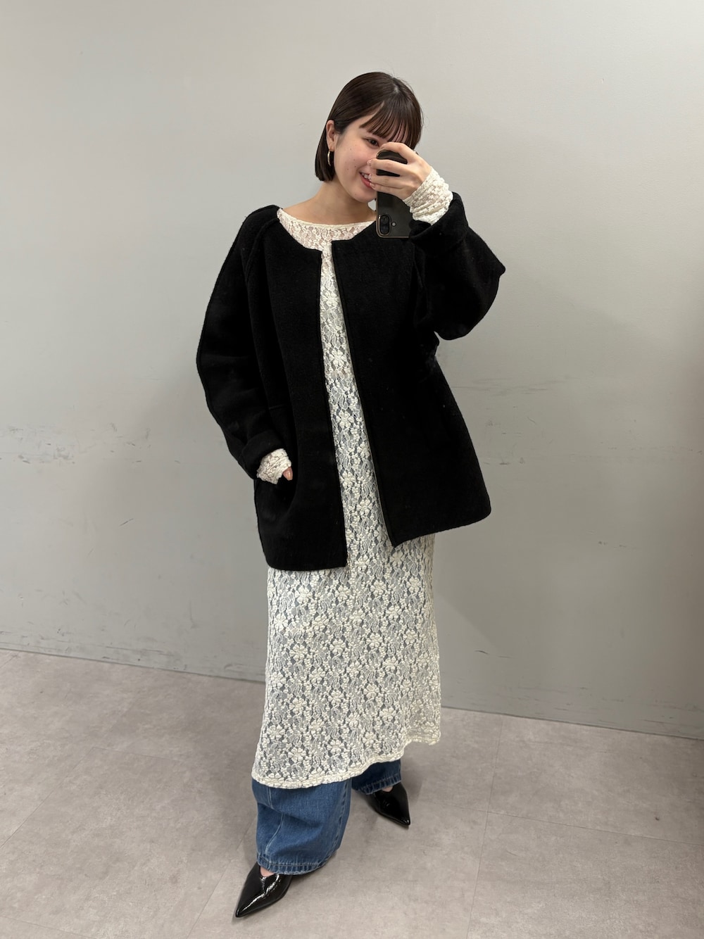 ブラック系のその他アウター、ホワイト系のワンピース、ブルー系のデニムパンツを着用したレディースの秋コーディネートの1枚目の写真