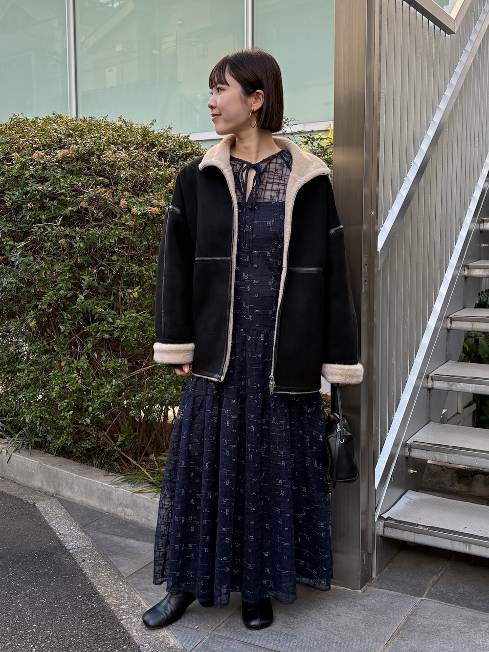 ブラック系のムートンコート、ブラック系のブーツ、ブラック系のワンピースを着用したレディースの秋コーディネートの1枚目の写真